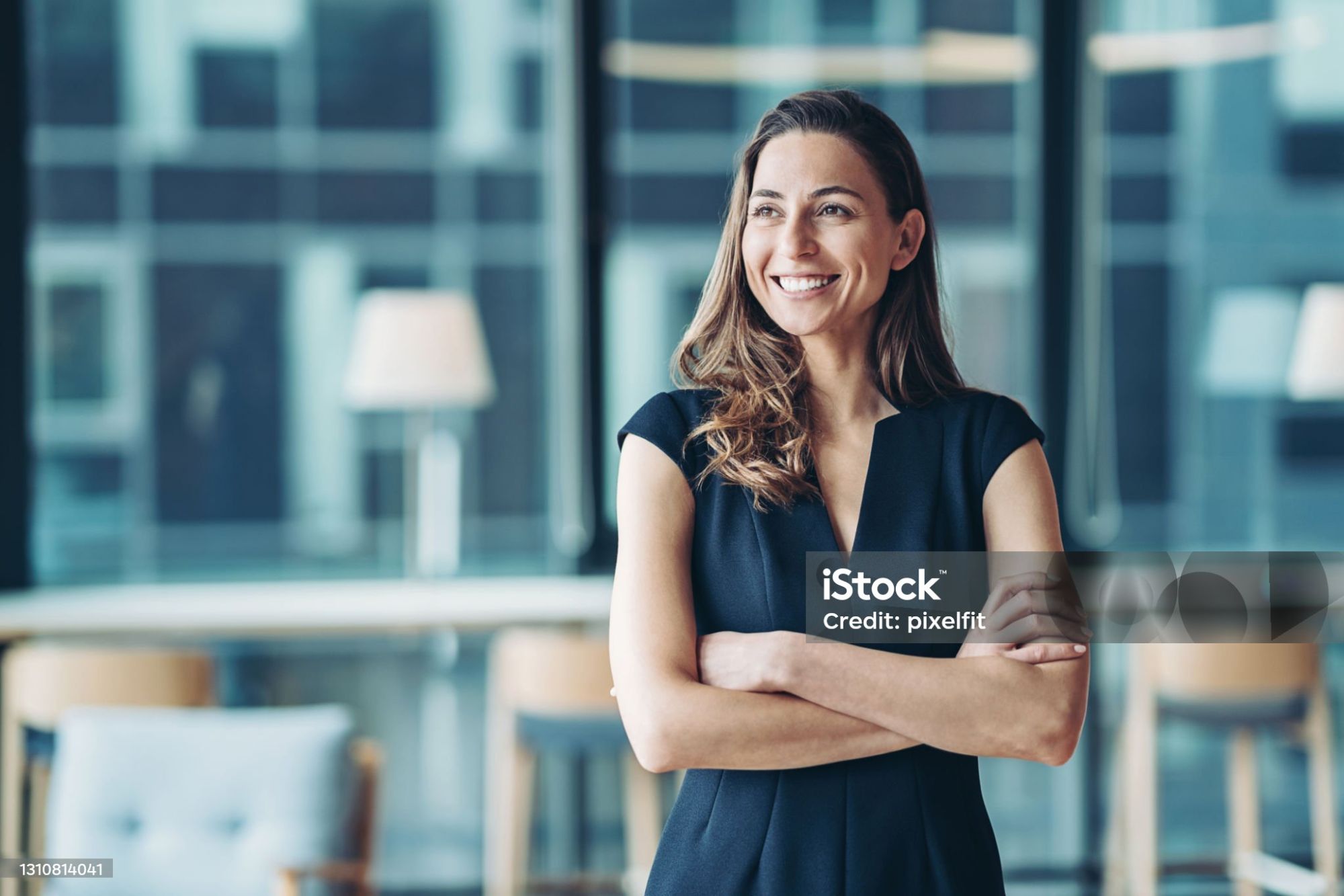 Smiling business owner standing with arms folded in a bright office